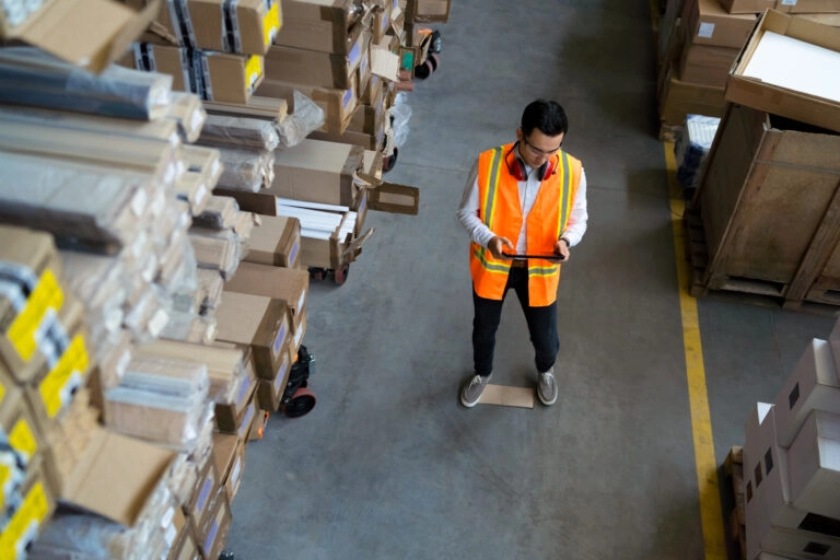 Ein Lagermitarbeiter überprüft mit einem Tablet das Lagermanagement.